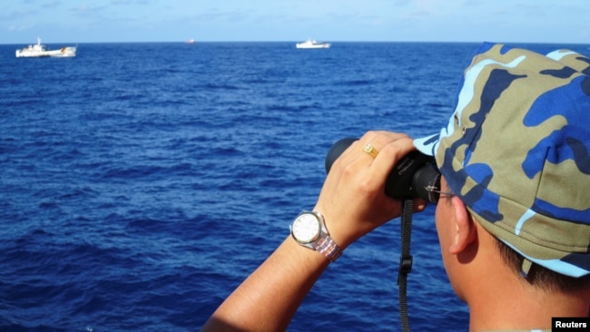 资料照：一名越南海警船成员在有争议的南中国海上观察中国海警船。（2014年7月15日）