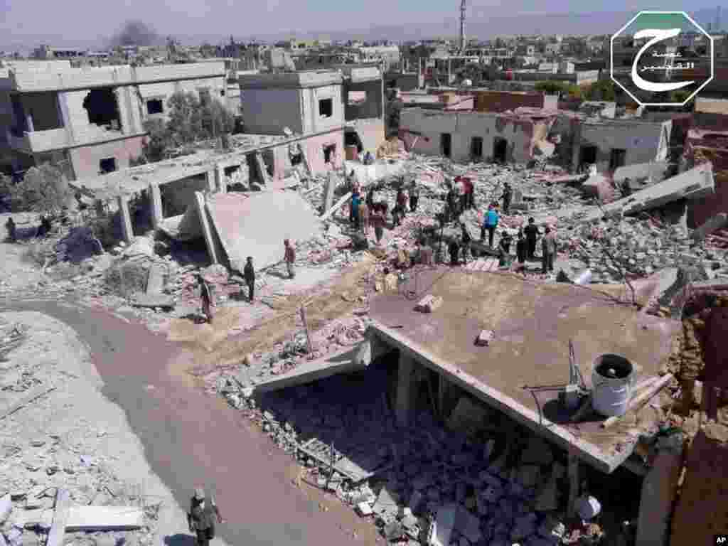 This citizen journalism image provided by Qusair Lens shows people gathered by houses that were destroyed in an airstrike in Qusair, Homs province, Syria, May 21, 2013. 