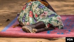A woman is sleeping outside Yoyo health center, Bidibidi refugee settlement. Many of those able to make the journey and cross the border into Uganda arrive in a worrying state of health after walking for days or weeks, often with no access to food and clean water, requiring immediate medical attention and humanitarian assistance. (N. Jidovanu/VOA)