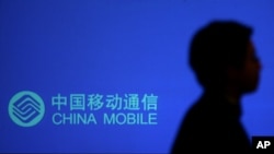 一名男子走過有中國移動標識的廣告牌。