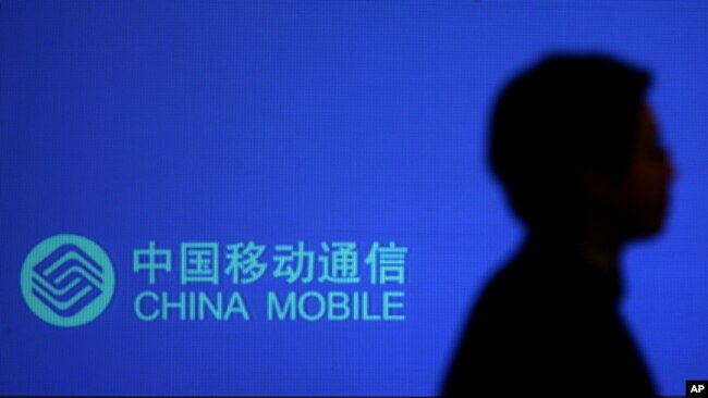 一名男子走过有中国移动标识的广告牌。