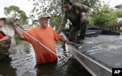 John Paul Klotz, 80, center, pulls his cane out of floodwaters as U.S. Border Patrol Agent Steven Blackburn stands by to help Klotz board a boat during a search-and-rescue operation in a neighborhood inundated by Tropical Storm Harvey in Houston, Texas, Aug. 30, 2017.