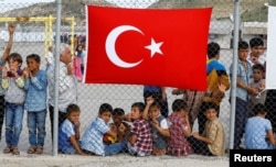 FILE - Refugees wait for the arrival of officials at Nizip refugee camp near Gaziantep, Turkey, April 23, 2016.