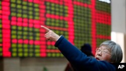 FILE - An investor gestures in front of the stock price monitor at a private securities company in Shanghai, China. 