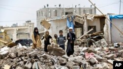 A boy and his sisters watch graffiti artists spray on a wall, commemorating the victims who were killed in Saudi-led coalition airstrikes in Sana'a, Yemen, May 18, 2015. 