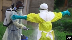 In this photo taken Sept. 9, 2018, a health worker sprays disinfectant on his colleague after working at an Ebola treatment centre in Beni, Eastern Congo.