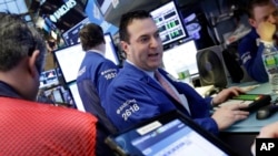 Specialist James Sciulli, center, works with traders at his post on the floor of the New York Stock Exchange, Feb. 22, 2016. Stocks are jumping Monday as the price of oil surges, lifting energy stocks. 