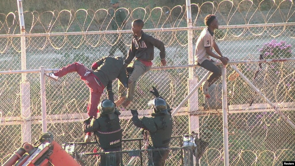 FILE - African migrants in this still image from video climb the border from Morocco to Spain's North African enclave of Ceuta, Spain, July 26, 2018. 