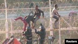 FILE - African migrants in this still image from video climb the border from Morocco to Spain's North African enclave of Ceuta, Spain, July 26, 2018.