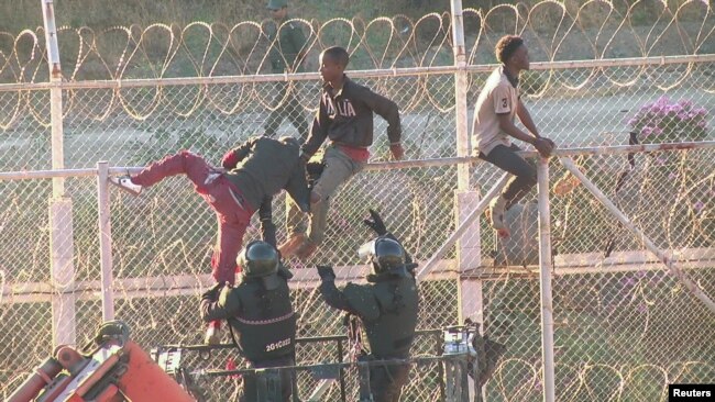 FILE - African migrants in this still image from video climb the border from Morocco to Spain's North African enclave of Ceuta, Spain, July 26, 2018.