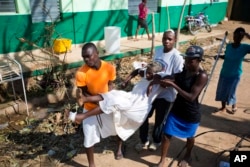 A woman with cholera is carried by residents to a cholera center in Anse D'Hainault, Haiti, Oct. 11, 2016.