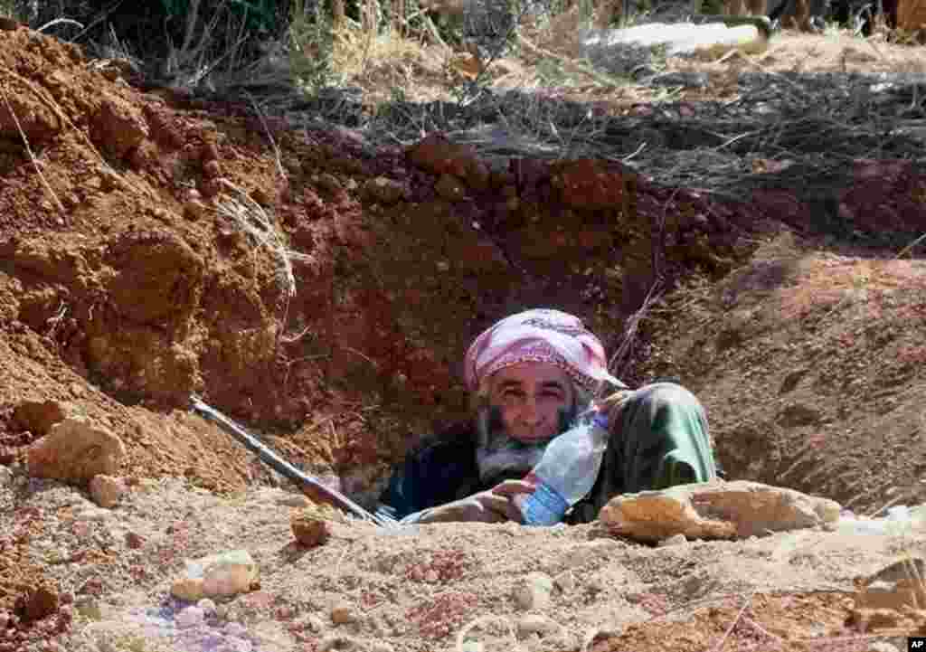 This citizen journalism image provided by ENN shows a Syrian rebel in a trench, in Idlib province, northern Syria, June 12, 2013. 