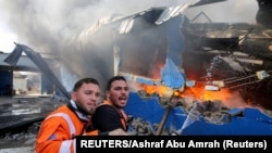 Des pompiers palestiniens essayent d'éteindre le feu dans une usine d'éponges après des tirs d'obus israéliens dans le nord de la bande de Gaza le 17 mai 2021.
