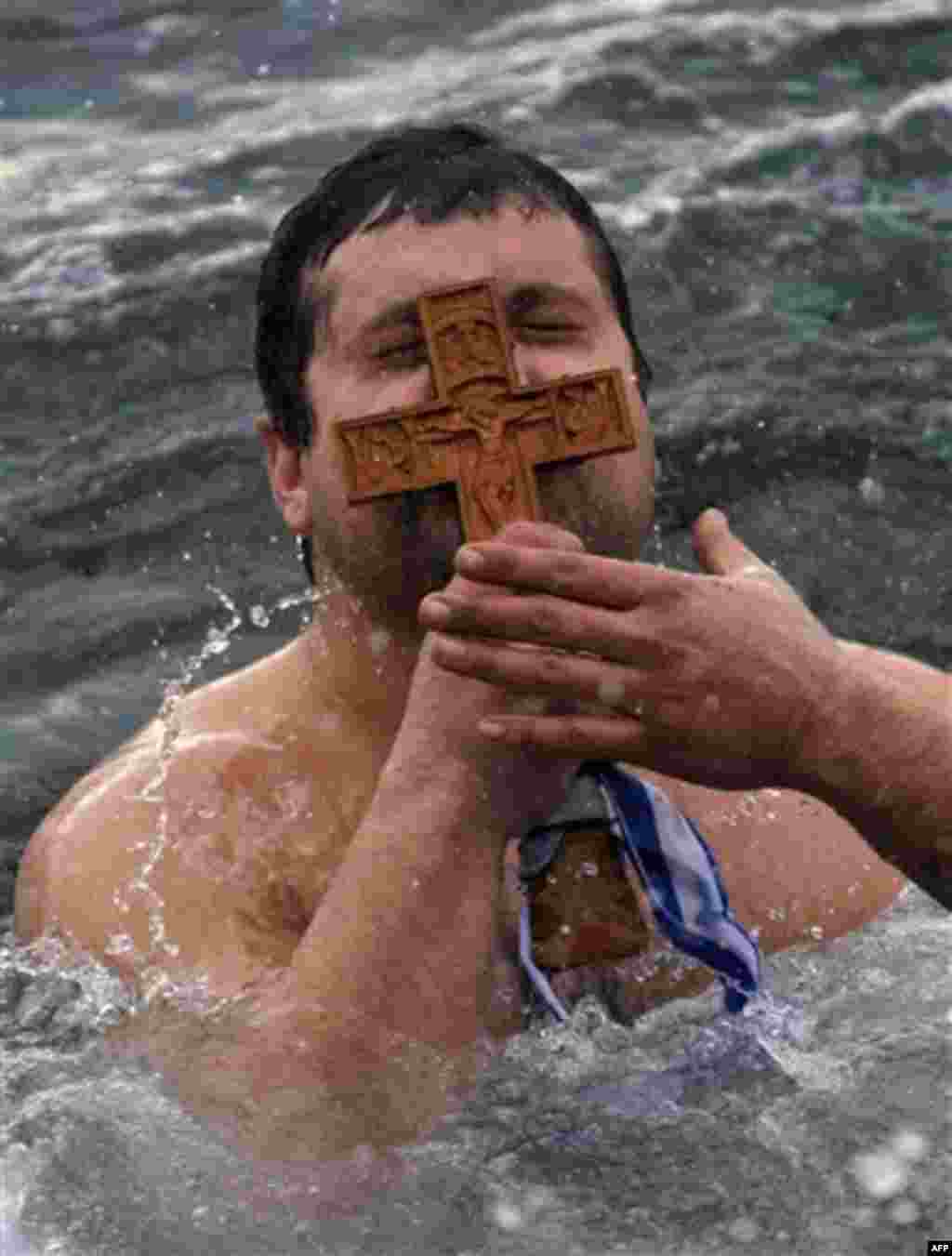 Panagiotis Mantziaris, kisses the wooden cross after being the first to retrieve it, during an Epiphany ceremony to bless the water in Greece's northern port city of Thessaloniki, Friday, Jan. 6, 2012. Similar ceremonies to mark Epiphany day were held acr