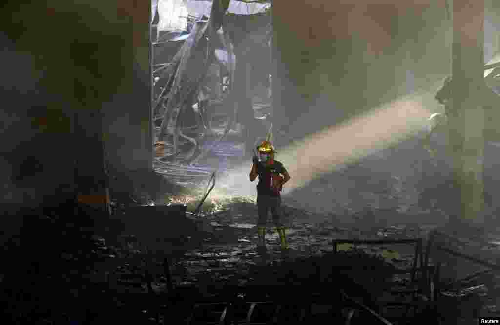 An arson investigator talks on a two-way radio inside a gutted slipper factory in Valenzuela, Metro Manila, the Philippines. A fire at the factory killed 31 workers and dozens were missing and feared dead, officials said.