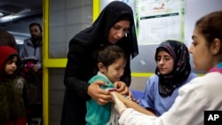 A Syrian girl cries after receiving the measles vaccine from UNICEF nurses Nadine Houjairi (2nd R), and Genivieve Bashalani (R) at the U.N. refugee agency's registration center in Zahleh, in Lebanon's Bekaa Valley, Dec. 18, 2013.