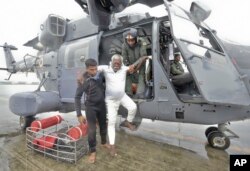 An Indian fisherman who was stranded in the Arabian Sea is escorted down from an Indian navy helicopter after being rescued in Thiruvananthapuram, Kerala state, India, Dec.1, 2017. Dozens of fishermen were rescued from the sea, which was very rough under the influence of Cyclone Ockhi.