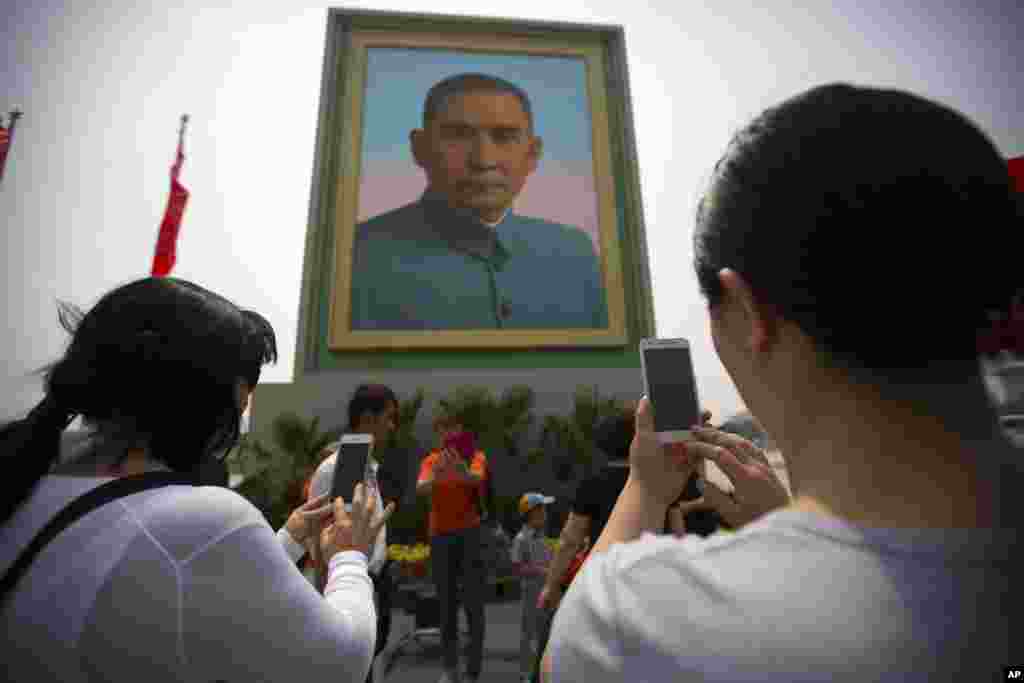 Pessoas na Praça de Tiananmen tiram fotografias a um retrato de Sun Yat-sen, figura reconhecida como o fundador da China moderna, na véspera do feriado de 1 de Maio em Pequim. Milhões de chineses aproveitam o feriado de 1 de Maio para viajar. 30 Abril, 2016&nbsp;&nbsp;