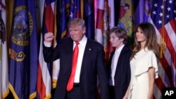 Presiden terpilih Amerika Serikat, Donald Trump, seusai memberikan pidato kemenangan di New York, 9 November 2016, didampingi oleh istrinya, Melania Trump (kanan) dan putra mereka, Barron Trump (AP Photo/John Locher).