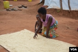 A woman in Souther district of Mwanza dries maize husks in the sun, readying them for milling. (L. Masina/VOA)