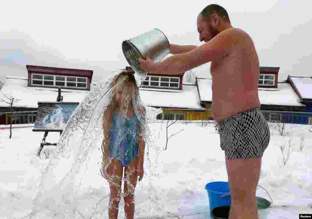 Grigory Broverman, a member of the Cryophile winter swimmers club, pours a bucket of cold water over his 9-year-old daughter Liza during a celebration of Polar Bear Day at the Royev Ruchey zoo, with the air temperature at about minus 5&deg; C, in Krasnoyarsk, Russia, Nov. 24, 2018.