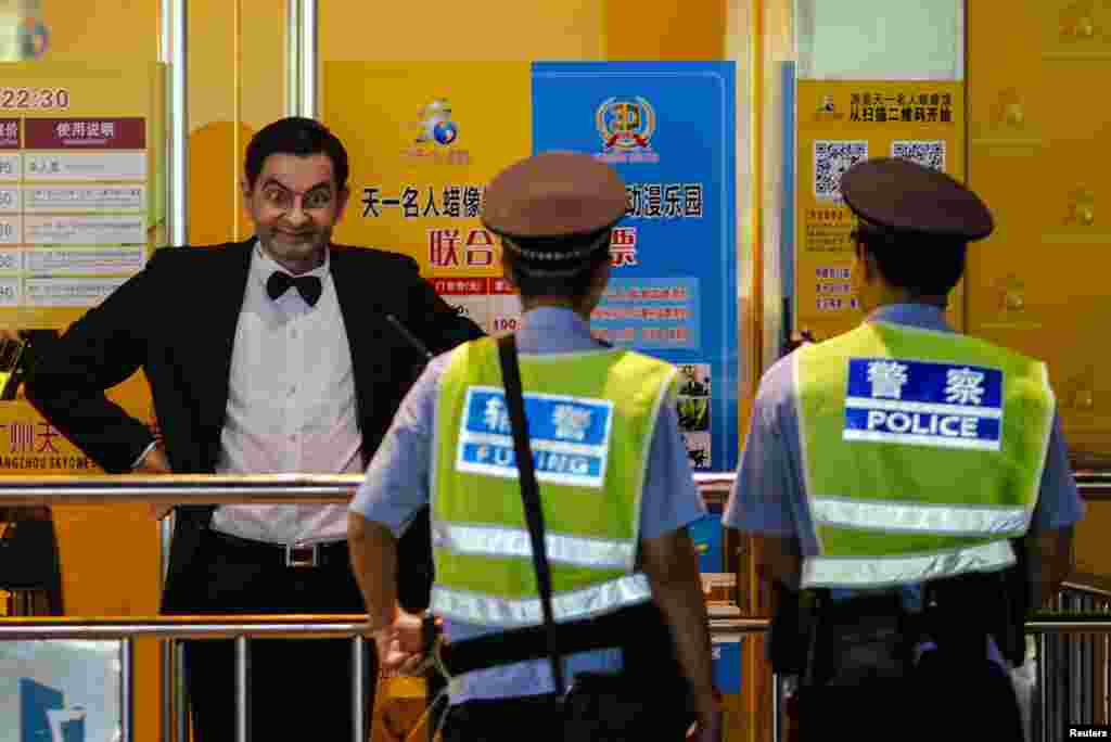 Policemen look at a wax figure of Rowan Atkinson, dressed as his popular television character Mr. Bean, on display outside a wax figure museum in Guangzhou, Guangdong province, China.