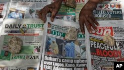 Seorang pedagang surat kabar menindih koran dagangannya dengan batu agar korannya tidak tertiup angin di sebuah lapak di Kano, utara Nigeria, Minggu, 24 Februai 2019 (foto: AP Photo/Ben Curtis)