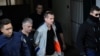 FILE - Alexander Vinnik, a Russian suspected of running a money-laundering operation using bitcoin, is escorted by police officers while leaving a court in Thessaloniki, Greece, Oct. 11, 2017.