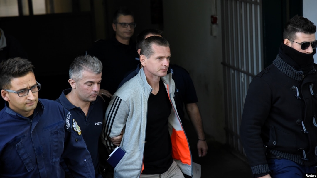 FILE - Alexander Vinnik, a Russian suspected of running a money-laundering operation using bitcoin, is escorted by police officers while leaving a court in Thessaloniki, Greece, Oct. 11, 2017.