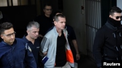 FILE - Alexander Vinnik, a Russian suspected of running a money-laundering operation using bitcoin, is escorted by police officers while leaving a court in Thessaloniki, Greece, Oct. 11, 2017.