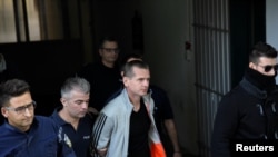 FILE - Alexander Vinnik, a Russian suspected of running a money laundering operation using bitcoin, is escorted by police officers while leaving a court in Thessaloniki, Greece, October 11, 2017.