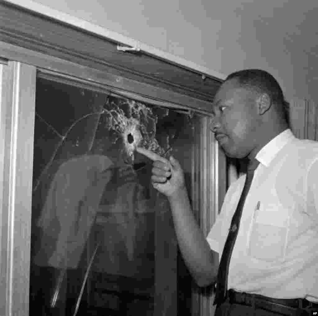 Integration leader Dr. Martin Luther King looks at a glass door of his rented beach cottage in St. Augustine, Fla. that was shot into by someone unknown on June 5, 1964. King took time out from conferring with St. Augustine integration leaders to inspect