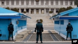 2014年南北朝鲜的非军事区板门店： 朝鲜士兵(上左)目视面对朝鲜的韩国士兵