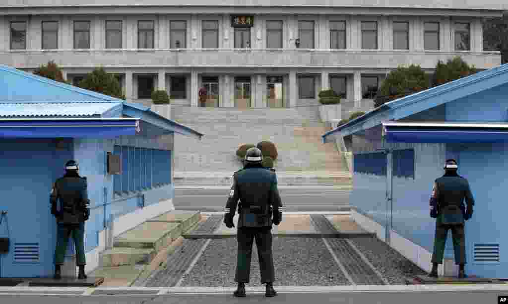 A N. Korean soldier (top center) looks at the southern side as three S. Korean soldiers guard at the border village of Panmunjom.