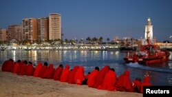 FILE - Migrants, part of a group intercepted aboard a dinghy off the coast in the Mediterranean Sea, rest after arriving on a rescue boat at the Port of Malaga, Spain.