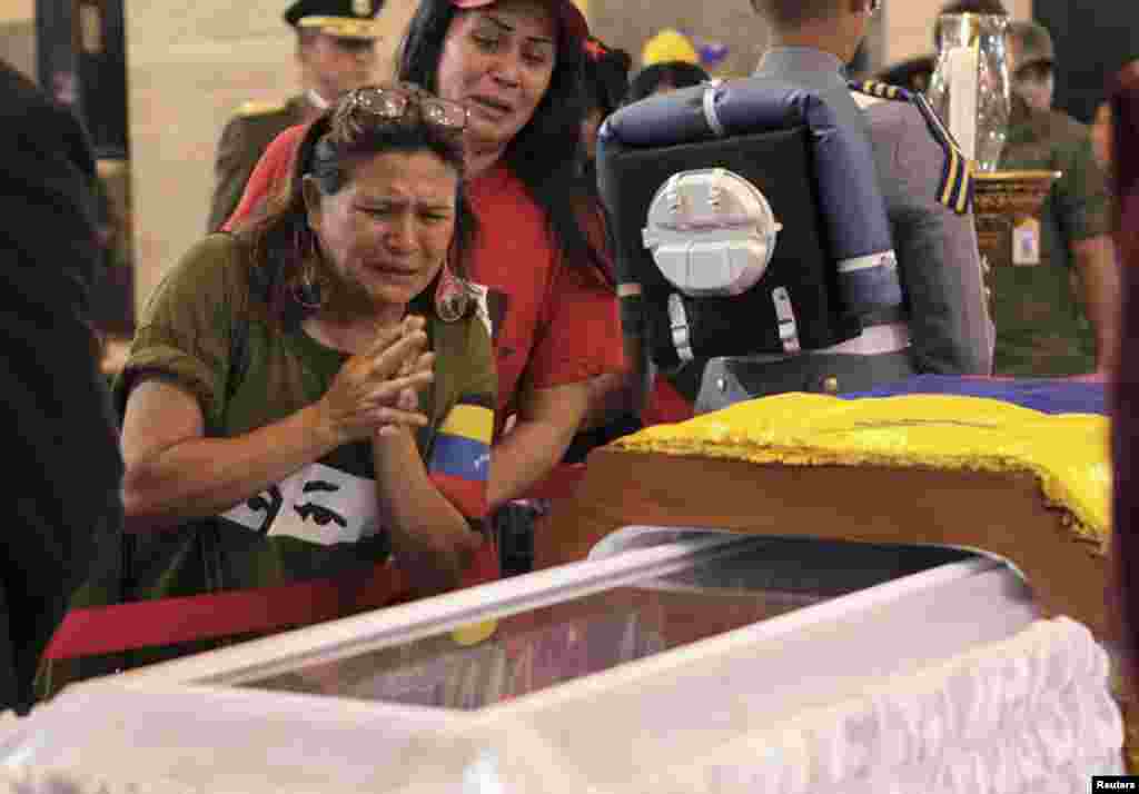 Supporters of late Venezuelan President Hugo Chavez react as they view his coffin during a wake at the military academy in Caracas, March 7, 2013.