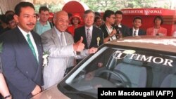 Putra bungsu Presiden Suharto dan Presiden PT Timor Hutomo Mandala Putra, Menteri Perdagangan dan Industri Indonesia Tunky Ariwibowo dan Wakil Ketua Kia Motors Korea Selatan Kim S-A. berpose di depan Timor produksi Korea Selatan, 8 Juli 1996. (Foto: AFP/John Macdougal)