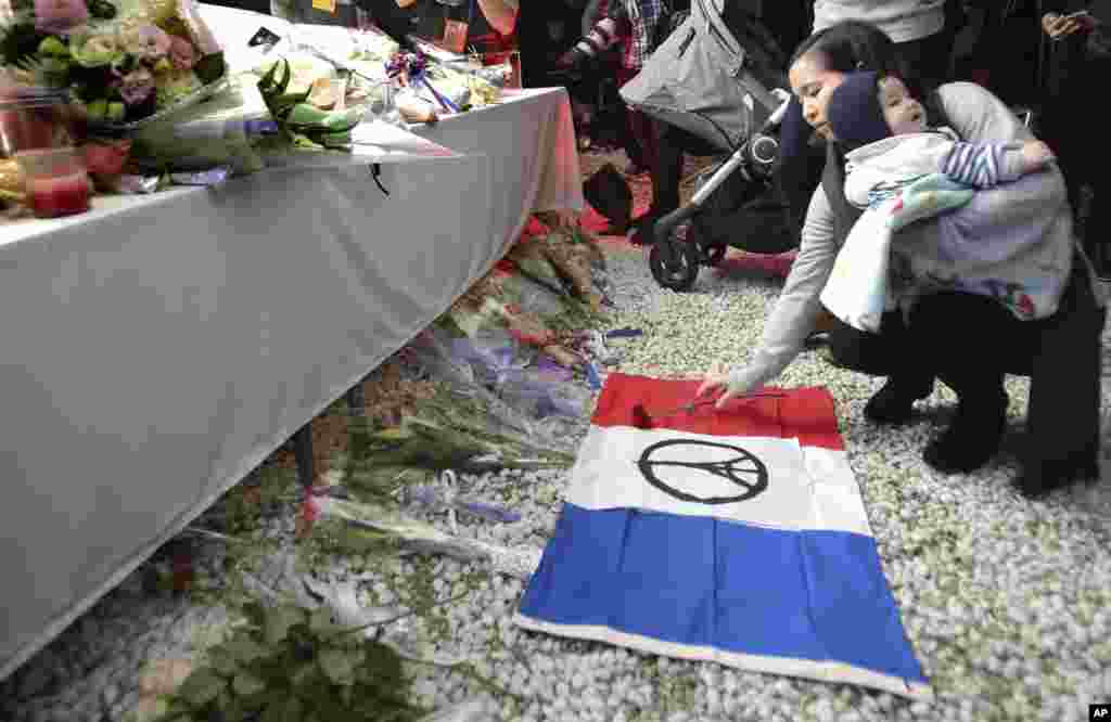 Seorang perempuan menaruh setangkai bunga dalam doa bersama bagi para korban serangan maut di Paris, di Kedutaan Besar Perancis di Tokyo (15/11). ​(AP/Shizuo Kambayashi)
