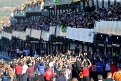 Pembalap MotoGP Valentino Rossi dari Italia, tengah, melambai pada akhir Grand Prix Sepeda Motor Valencia, balapan terakhir musim ini, di sirkuit Ricardo Tormo di Cheste, dekat Valencia, Spanyol, Minggu, 14 November 2021. (Foto: : AP)