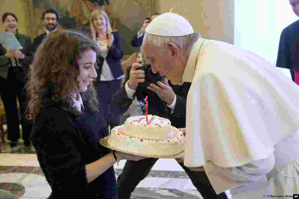 로마 가톨릭 프란치스코 교황이 바티칸에서 한 가톨릭 청소년 단체가 준비한 생일 케이크의 촛불을 끄고 있다.