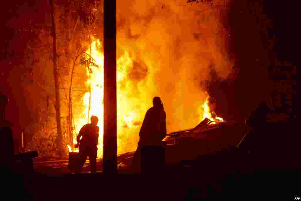 People work to put out a forest fire in Hualqui, 30 kilometres south of Concepcion, Biobio region, Chile. Raging forest fires in central Chile have killed 10 people, displaced thousands and destroyed entire villages.