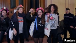 Activists of Ukrainian women's rights group Femen leave the Paris courthouse, Oct. 29, 2015, after they were acquitted in appeal over a topless demonstration they staged inside Notre-Dame Cathedral in February 2013. 