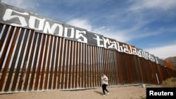 FILE - Activists have painted the U.S.-Mexico border wall between Ciudad Juarez and New Mexico as a symbol of protest against U.S. President Donald Trump's immigration reform in Ciudad Juarez, Mexico, Feb. 26, 2017. The paint reads "We are workers."