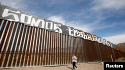 A group of activists paints the U.S.-Mexico border wall between Ciudad Juarez and New Mexico as a symbol of protest against U.S. President Donald Trump's new immigration reform in Ciudad Juarez, Mexico, Feb. 26, 2017. The paint reads "We are workers."