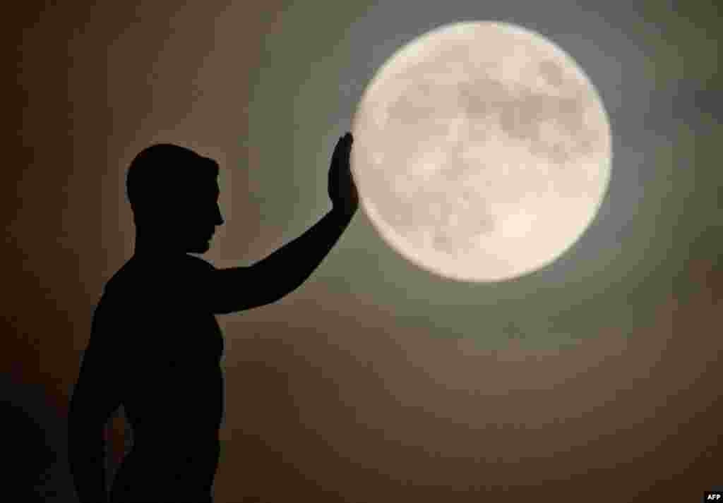 A sculpture is silhouetted against the full moon in Hanover, central Germany, Dec. 16, 2013.