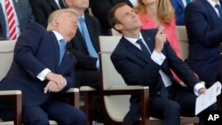 FILE - French President Emmanuel Macron, right, and U.S. President Donald Trump watch the traditional Bastille Day military parade, including military jet flyovers, on the Champs Elysees, in Paris, July 14, 2017. 