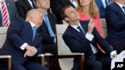 French President Emmanuel Macron, right, and U.S. President Donald Trump watch the traditional Bastille Day military parade, including military jet flyovers, on the Champs Elysees, in Paris, July 14, 2017.