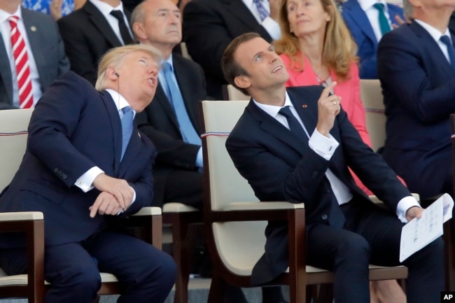 FILE - Then-U.S. President Donald Trump and French President Emmanuel Macron watch the traditional Bastille Day military parade, including military jet flyovers, on the Champs Elysees in Paris on July 14, 2017.