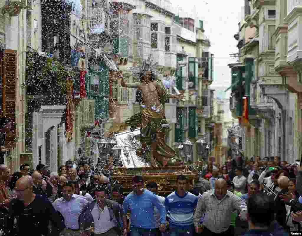 Worshipers run while carrying a statue of the Risen Christ as confetti streams down during an Easter Sunday procession in Cospicua, outside Valletta, Malta, April 5, 2015.