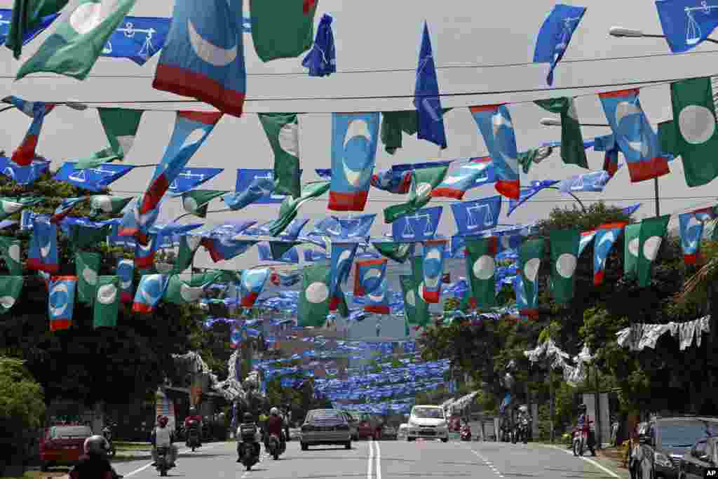 Motorists drive underneath flags of Malaysia's ruling party National Front, opposition Pan-Malaysian Islamic Party and People's Justice Party ahead of the upcoming general elections in Kuala Lumpur.
